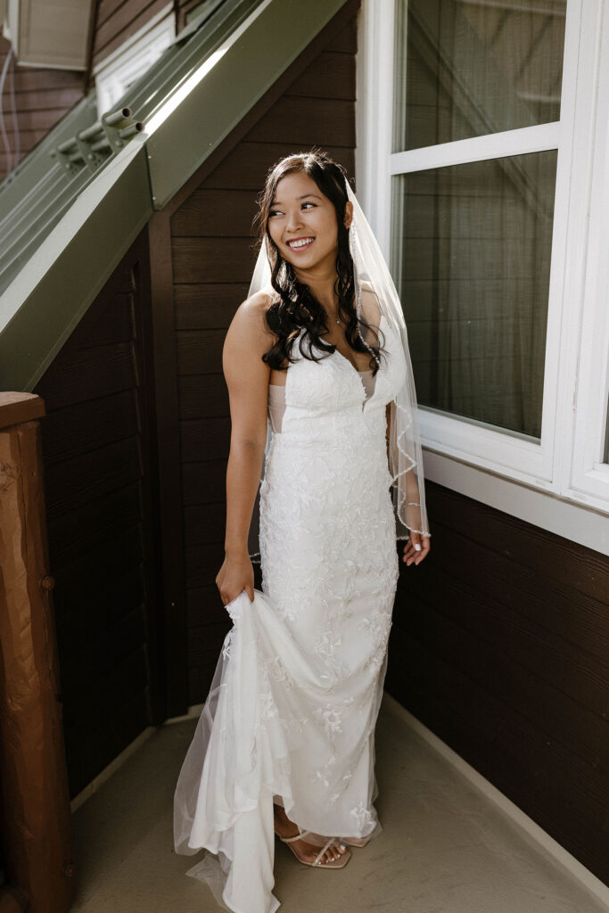 Elopement bride holding wedding dress while looking away from camera on balcony in Lake Tahoe