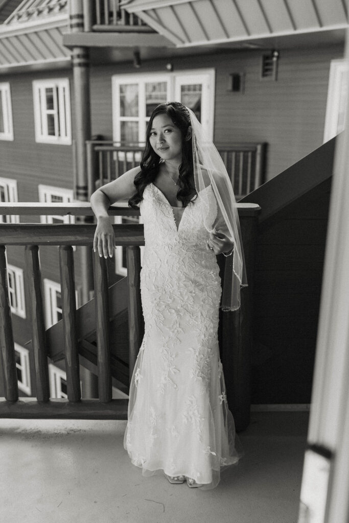 Elopement bride holding wedding veil while leaning on railing on balcony in Lake Tahoe