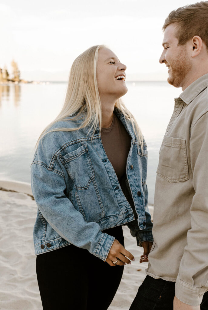 Engagement couple laughing with each other while at Meeks Bay with Lake Tahoe in background