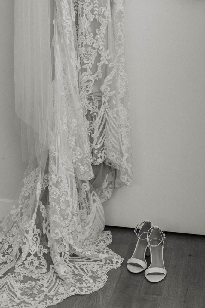Wedding dress hanging with lace trail next to wedding shoes in Lake Tahoe