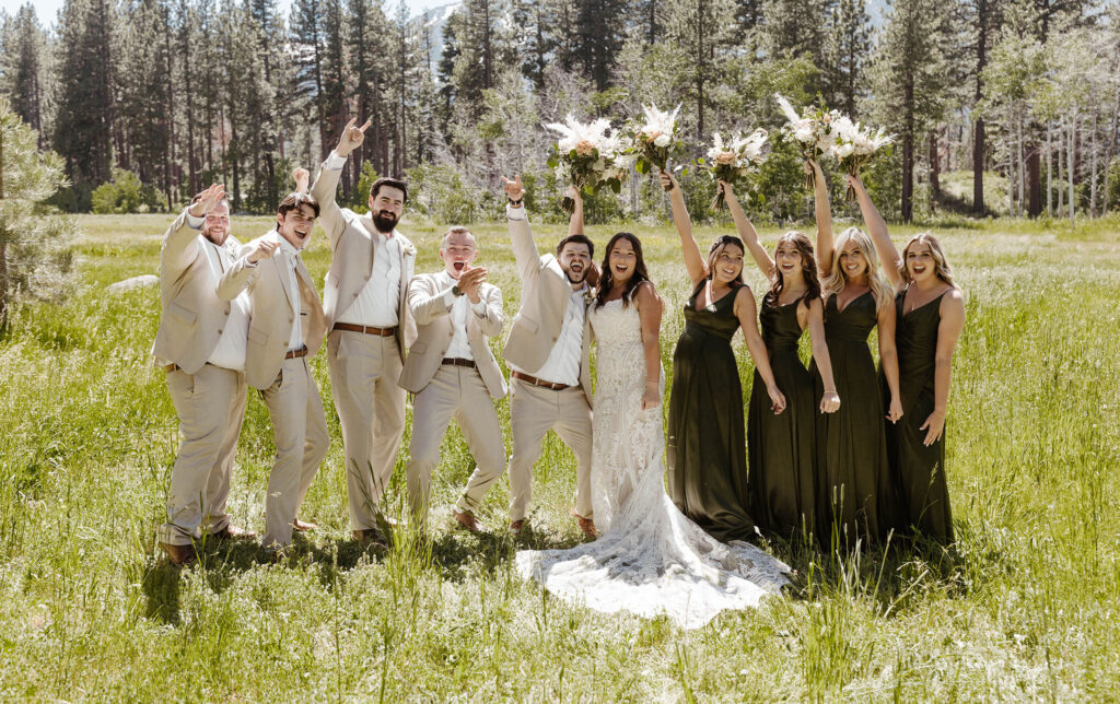 Wedding couple and bridal party standing together facing camera and celebrating while in a grassy meadow in Lake Tahoe