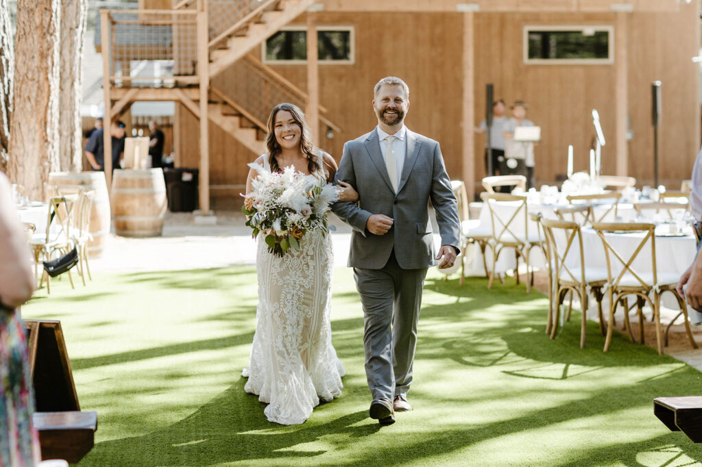 Wedding bride walking down aisle with dad while both smile in Lake Tahoe
