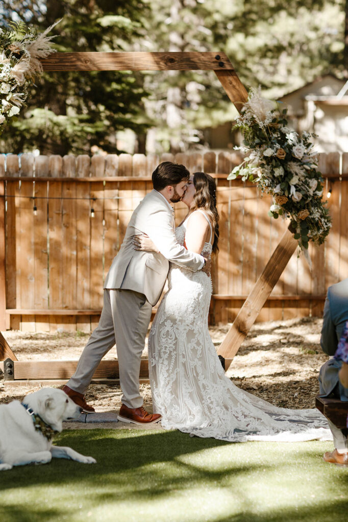 Wedding couple kissing while holding each other in front of wedding arch after ceremony in Lake Tahoe