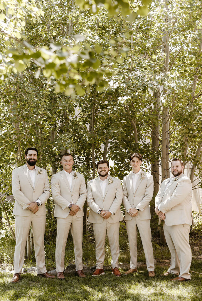 Groom and groomsmen standing and facing camera while smiling with hands clasped in Lake Tahoe