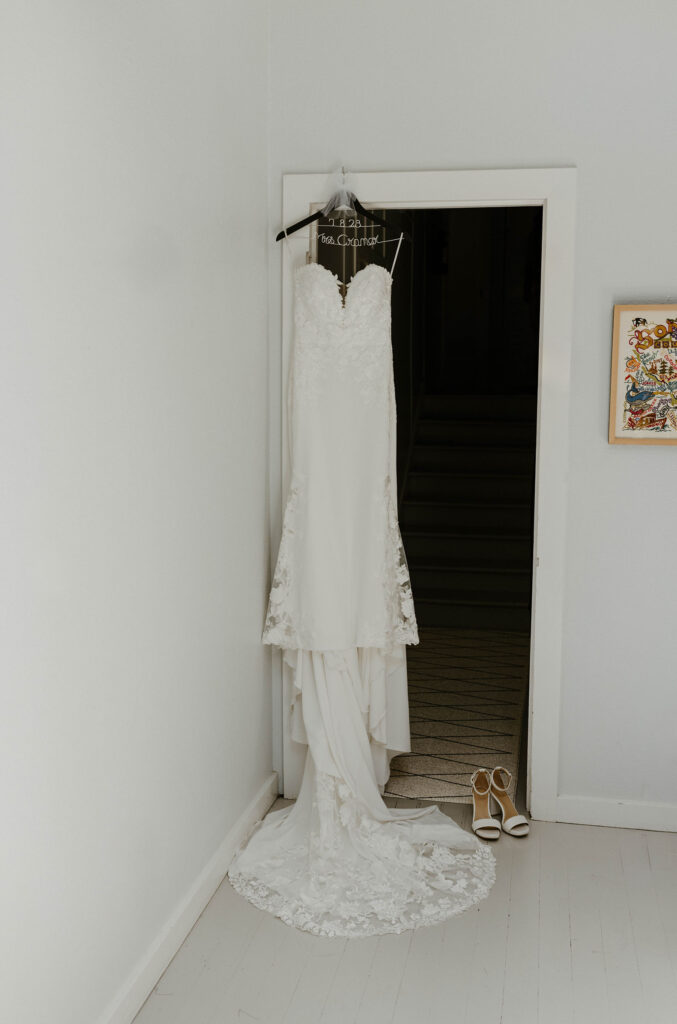Wedding dress hanging on door frame with white shoes beside it at French Oak Ranch
