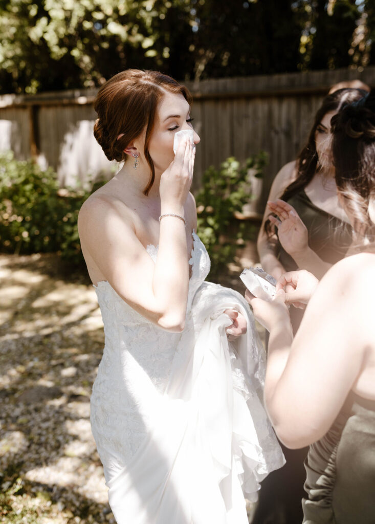 Wedding bride emotional and wiping tears after first look with bridesmaids at French Oak Ranch
