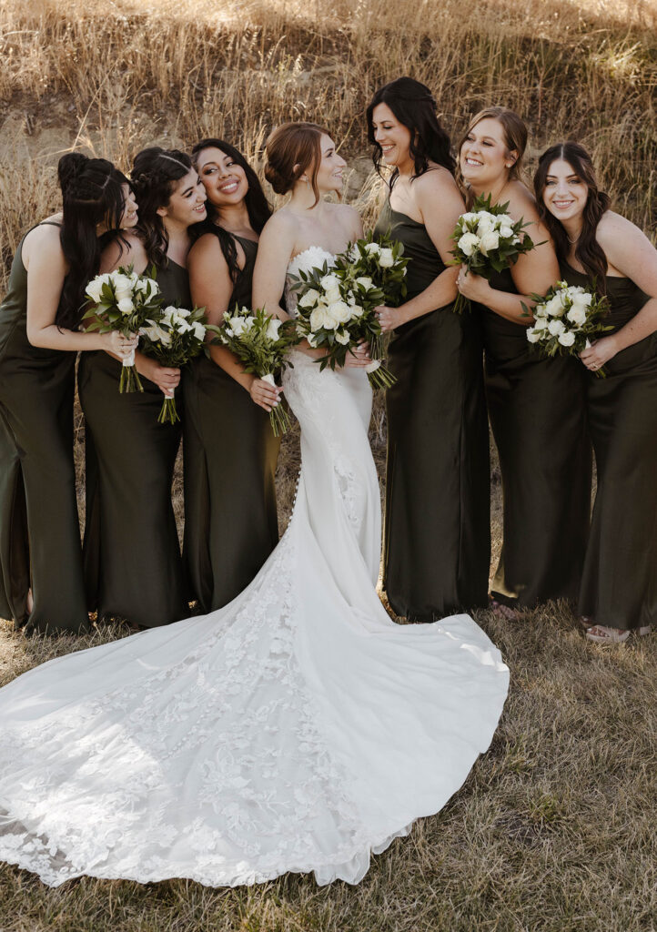 Wedding bride and bridesmaids smiling while holding white floral bouquets at French Oak Ranch