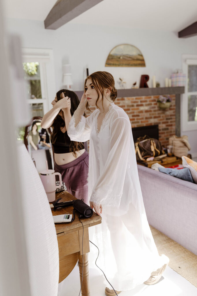Wedding bride looking in mirror and adjusting hair while inside at French Oak Ranch