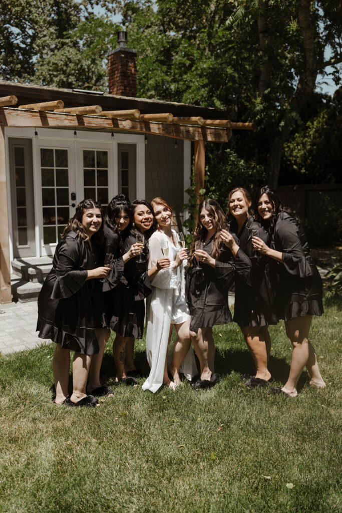 Bride and bridesmaids in wedding getting ready robes holding champagne glasses at French Oak Ranch