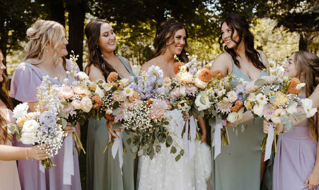 Wedding bride with bridesmaids holding colorful floral bouquets while smiling at Jacobs Berry Farm