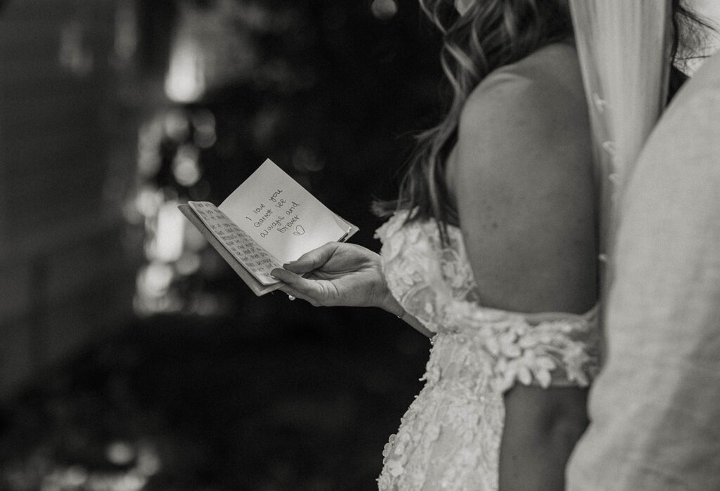Bride holding wedding vow book and reading to groom while outside at Jacobs Berry Farm
