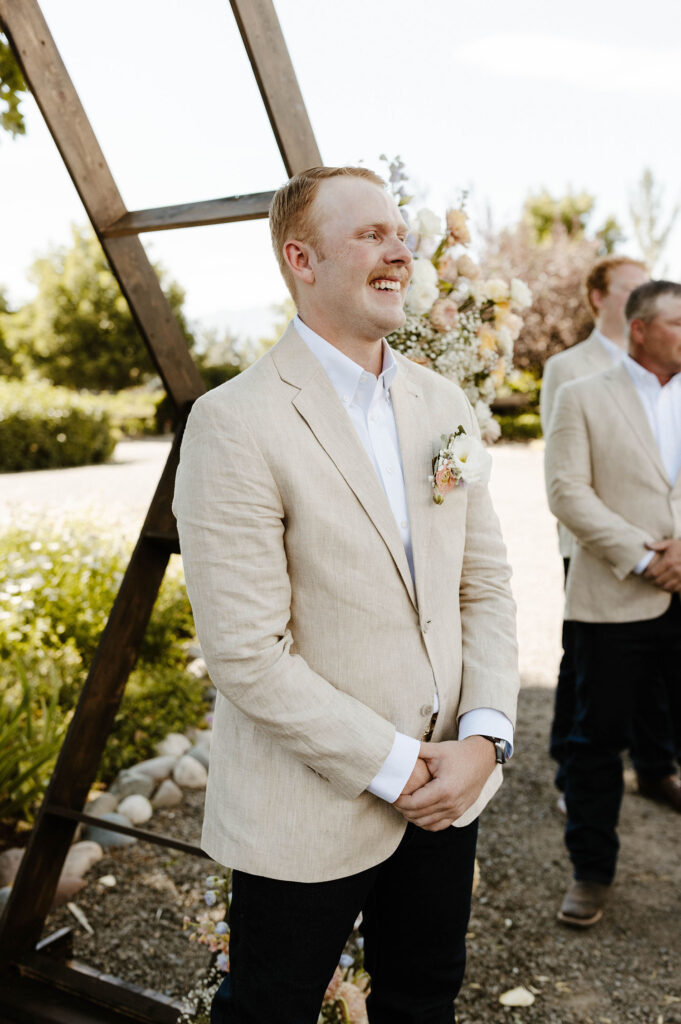 Groom emotional and smiling while watching bride walk down aisle during wedding ceremony at Jacobs Berry Farm