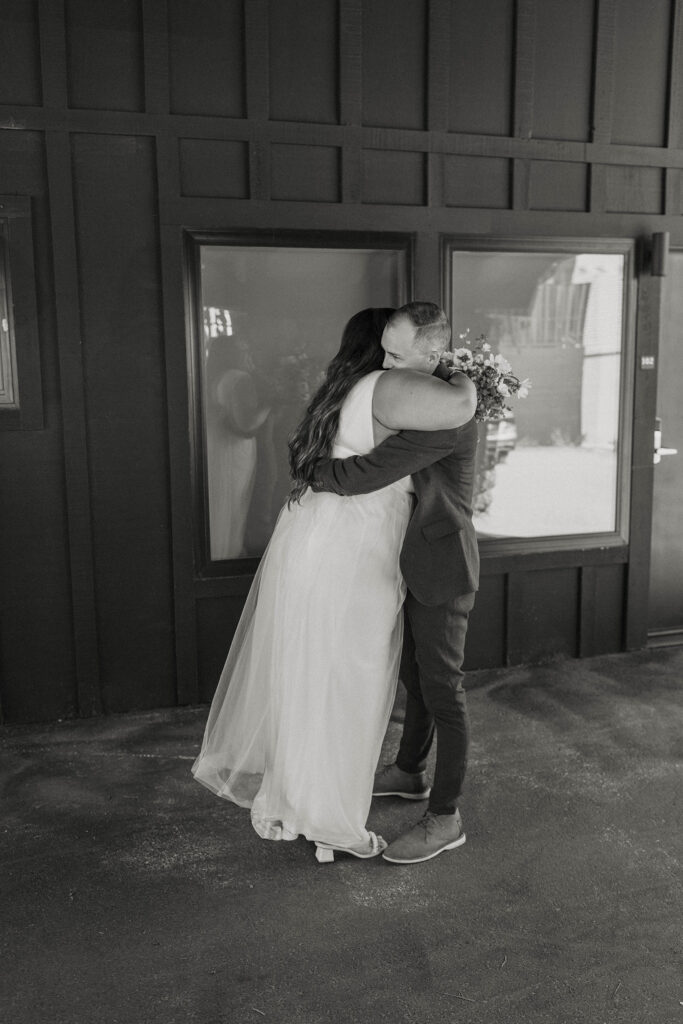 Wedding couple hugging while in front of large windows and building at the coachman hotel in Lake Tahoe
