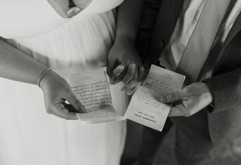 Wedding couple holding hands while holding up their written vows to each other at the coachman hotel in Lake Tahoe