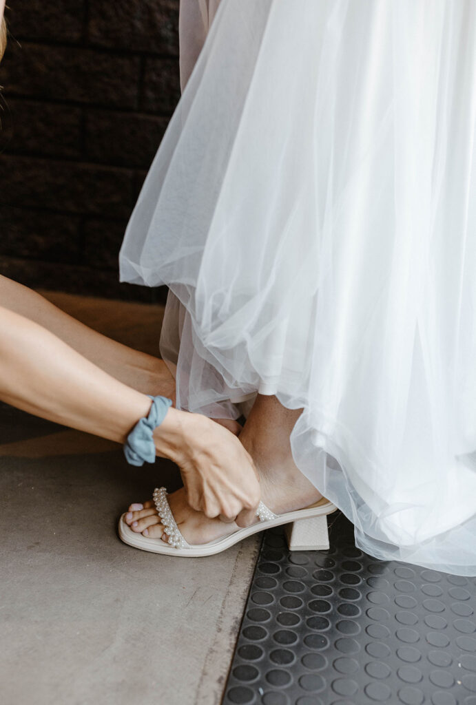 Bridesmaid fastening bride's wedding shoes while inside at the coachman hotel in Lake Tahoe