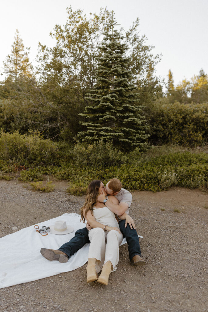 Married couple kissing while siting on blanket together on dirt trail at Donner Lake