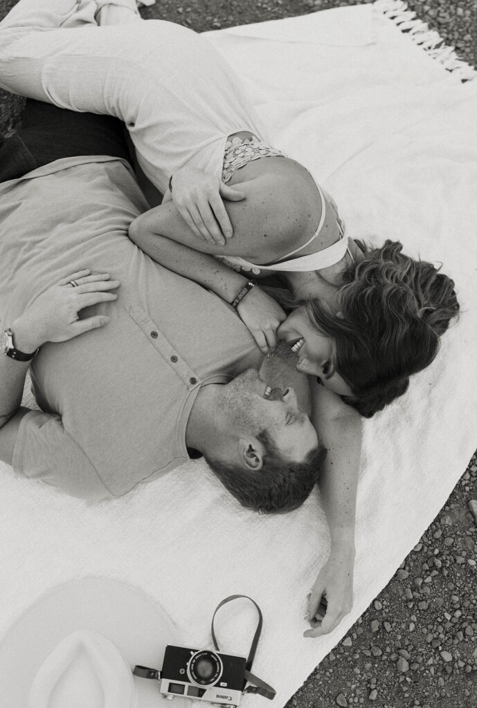 Married couple lying on blanket together and smiling at each other with old style camera on side at Donner Lake