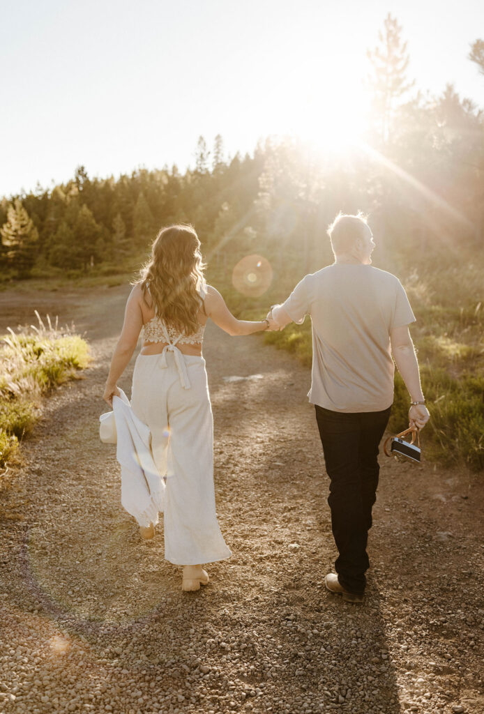 Married couple holding hands while walking down dirt trail together away from camera at Donner Lake
