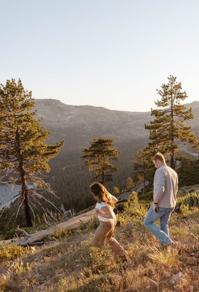 Married couple walking down hill together with long shadows and pine trees in background at Donner Lake