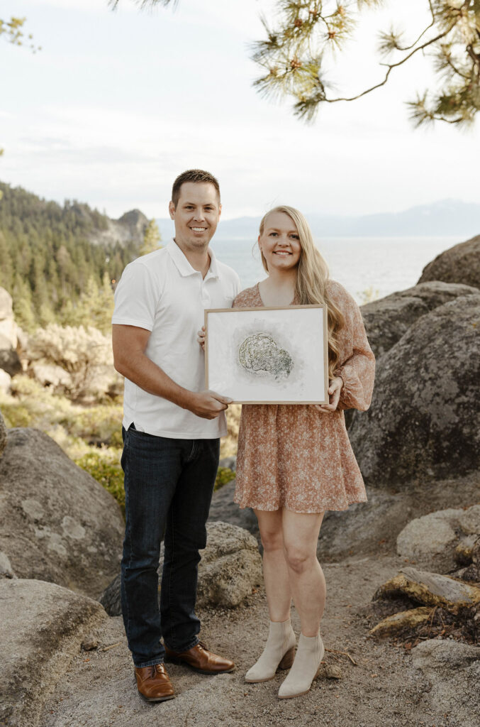 couple holding a frame smiling in lake tahoe during the summer