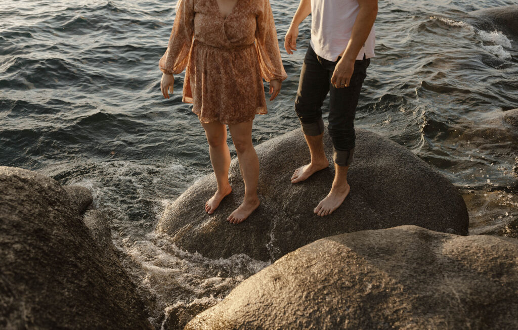 couple standing on a rock barefoot near the water in lake tahoe 