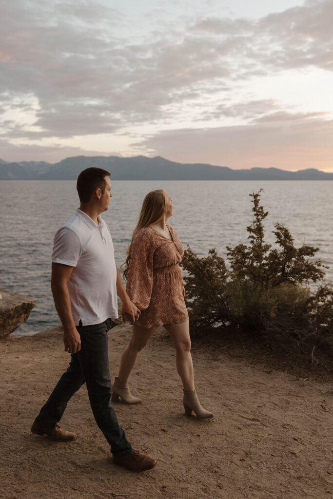 maternity couple walking on the sand holding hands at sunset in lake tahoe