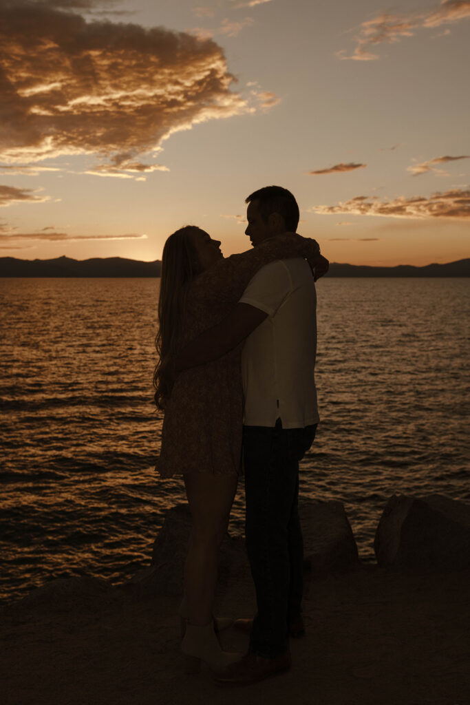 silhouette of a couple hugging overlooking lake tahoe at sunset 