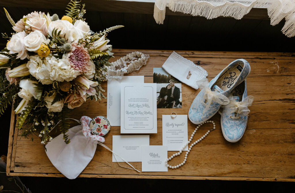 Wedding details in flat-lay with invites shoes and flowers on wooden table at Valhalla in Lake Tahoe