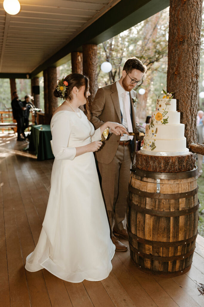 Wedding couple cutting wedding cake on wooden barrel together with knife at Valhalla in Lake Tahoe