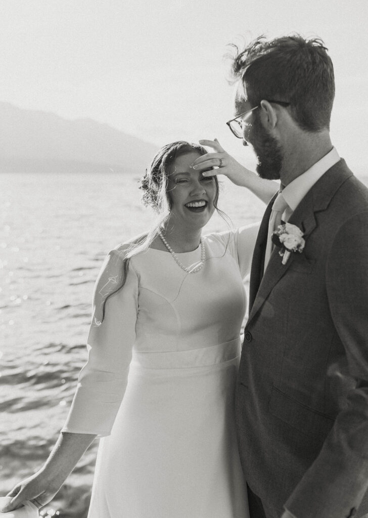 Wedding couple standing together as bride smiles with Lake Tahoe and mountains in background