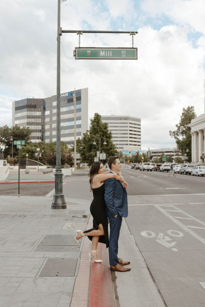 Woman hugging man from behind while he stands on side of street in downtown Reno
