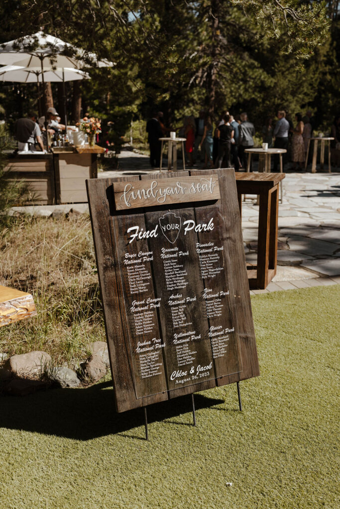 Wooden national park wedding guest seating sign on grass at dancing pines