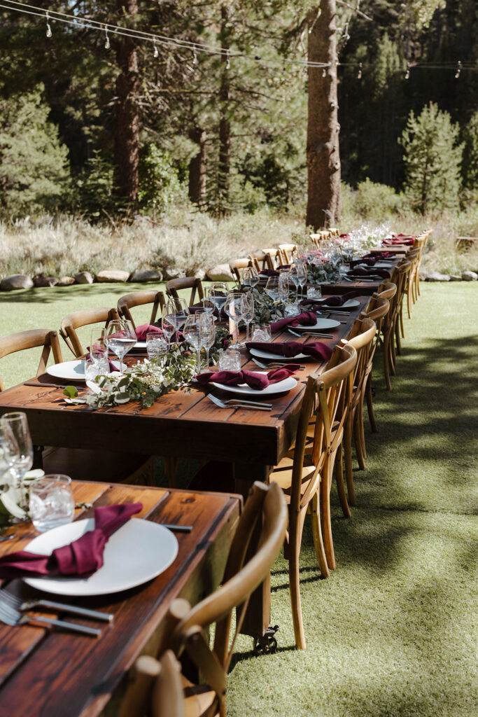 Wooden tables and chairs for wedding reception on grass at dancing pines