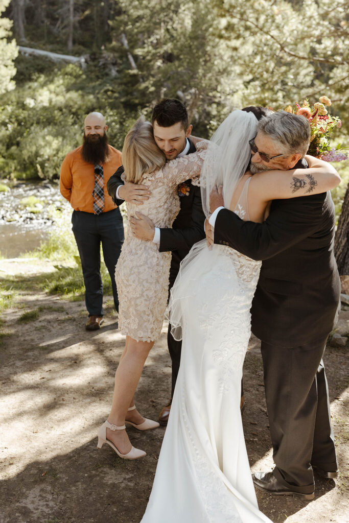 Groom and bride hugging parents before ceremony at dancing pines