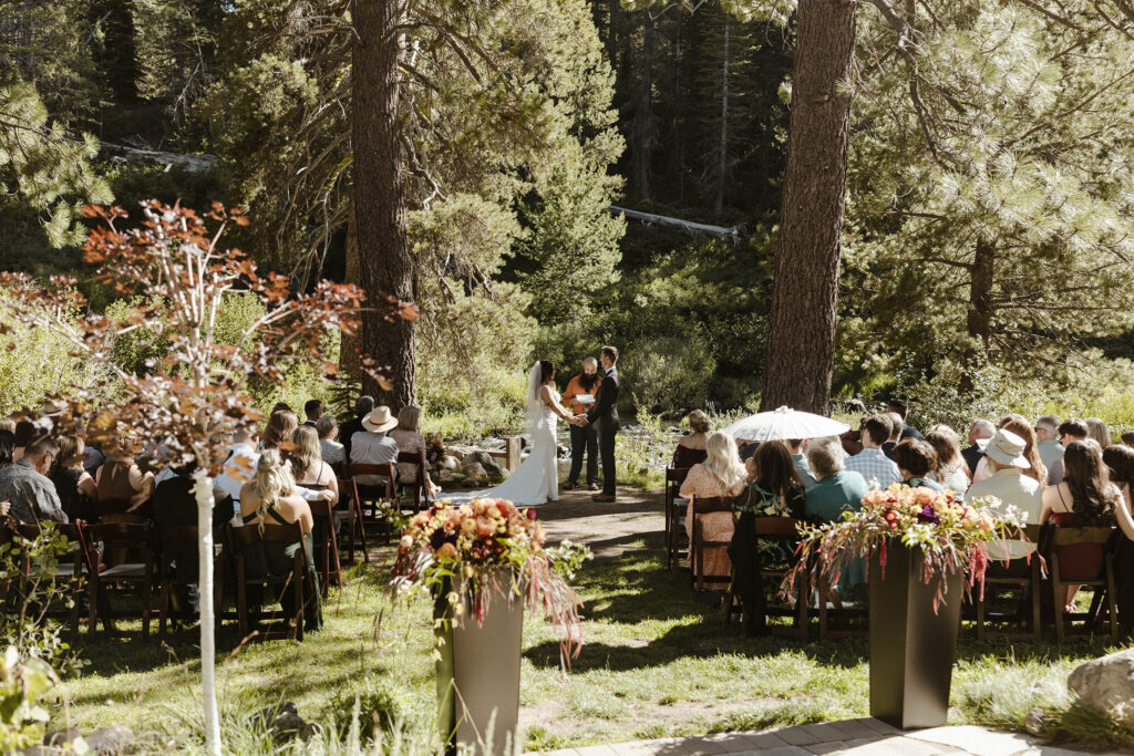 Wedding ceremony at dancing pines with tall planters and guests while surrounded by trees