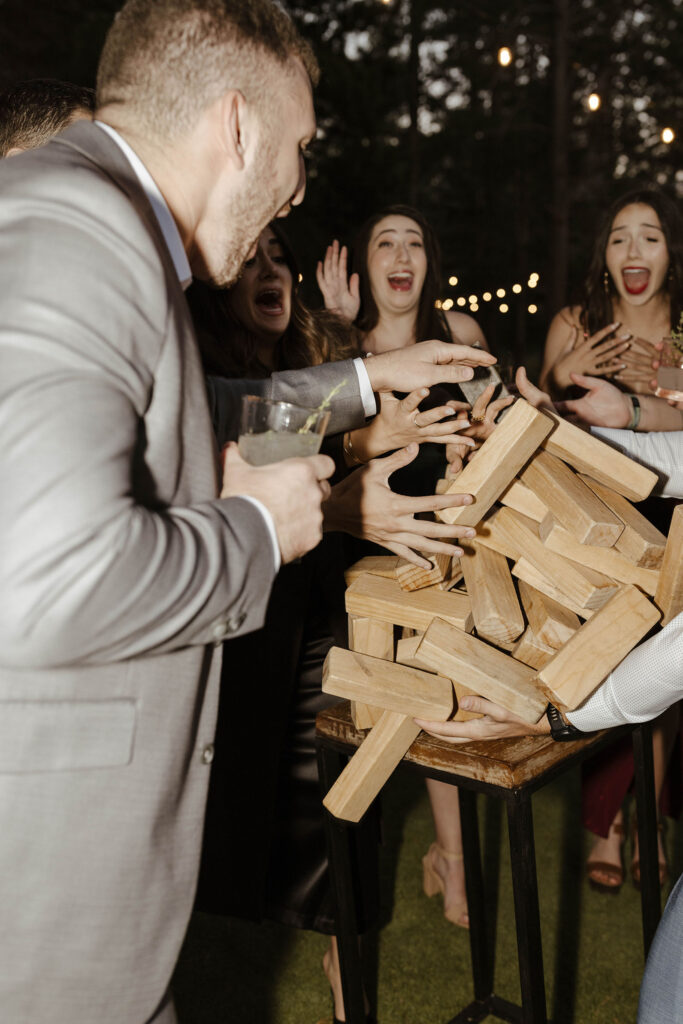 Wedding guests playing with large Jenga set during reception at dancing pines