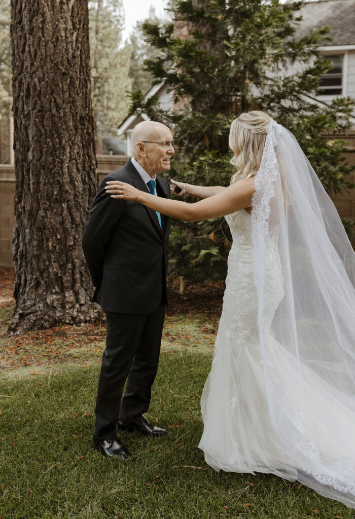 Wedding bride putting hands on Dad's shoulders during first look at Aspen Grove