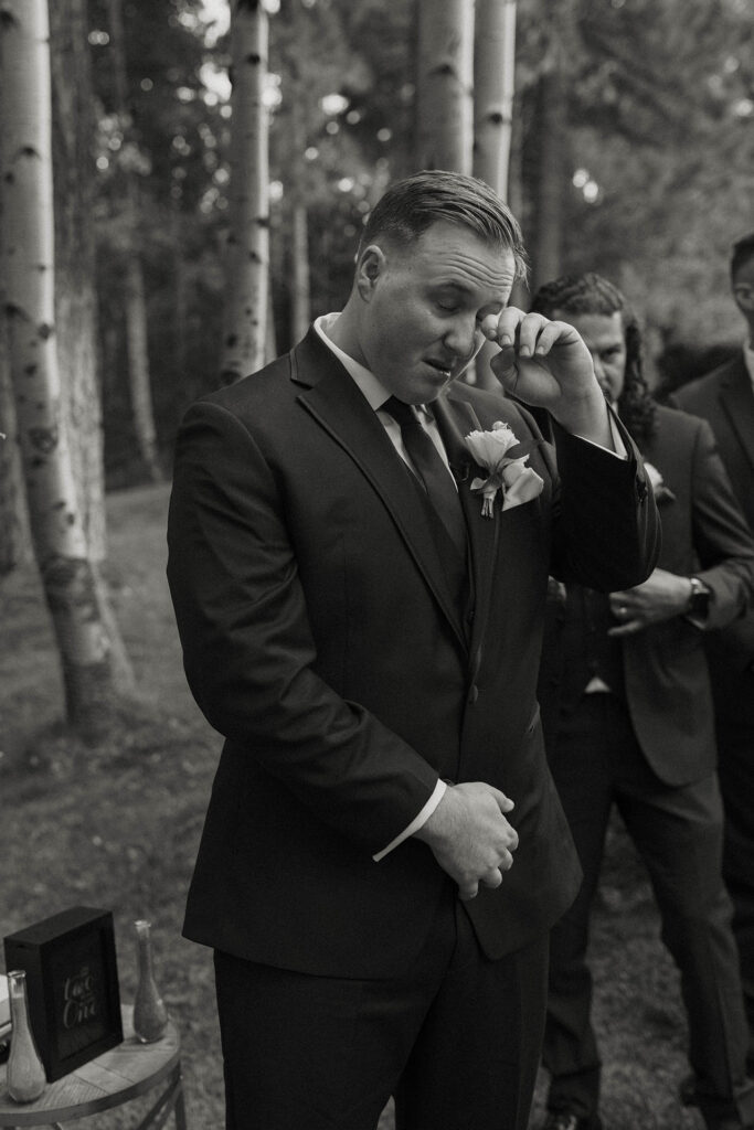 Wedding groom emotional while watching bride walk down aisle during ceremony at Aspen Grove