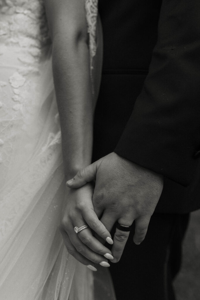 Close up of wedding couples hands holding each other while wearing wedding rings at Aspen Grove