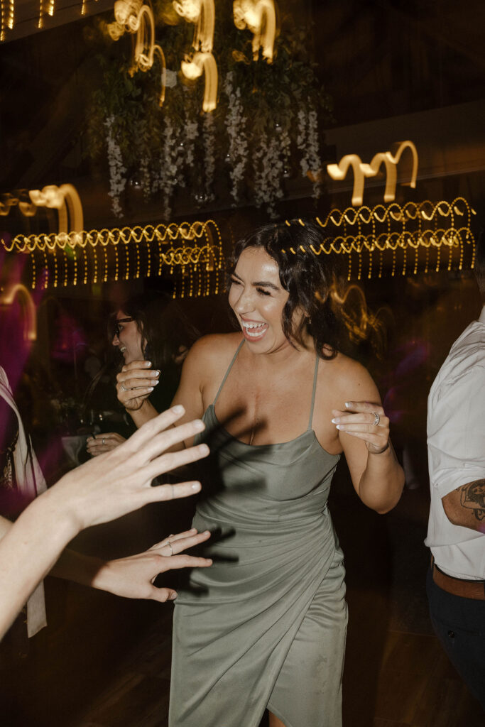 Wedding guests dancing and laughing while lights blur during reception inside at Aspen Grove