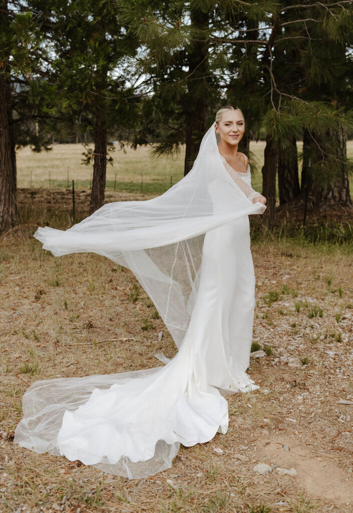 bride playing with her veil and smiling at kinship ranch