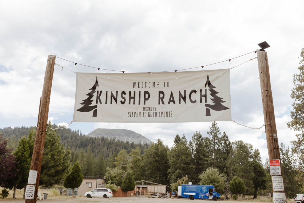 banner of Kinship Ranch hung on wooden posts overlooking the mountains