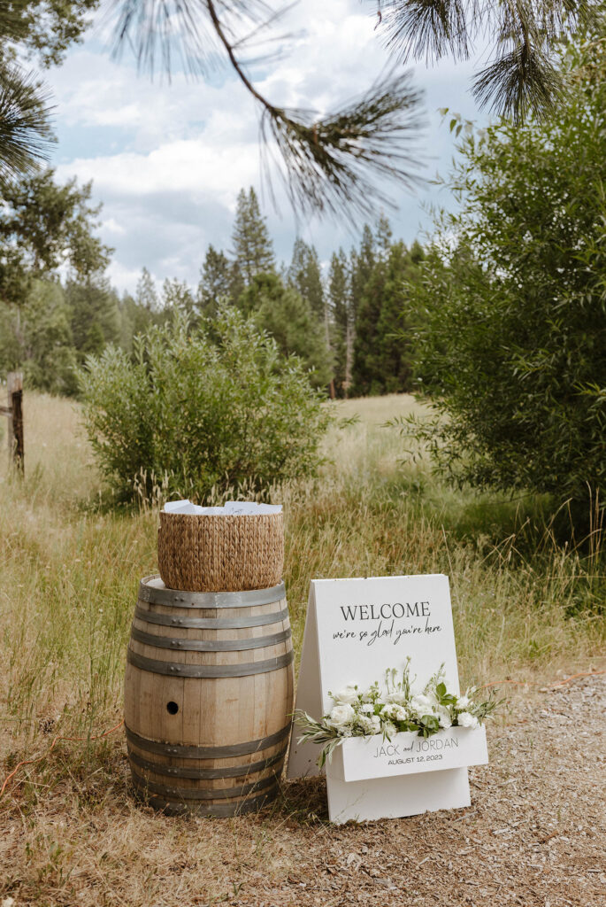 welcome sign with white roses and greenery at a summer wedding at kinship ranch