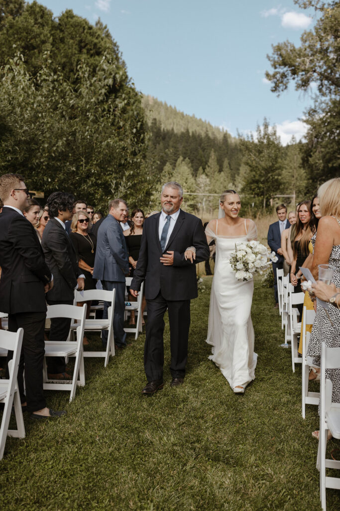 bride and her dad walking down the aisle during their summer ceremony at kinship ranch