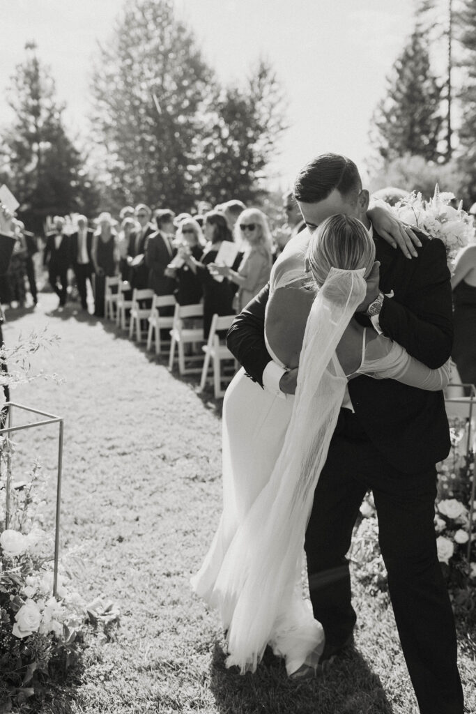 bride and groom kissing at the end of the aisle of their wedding ceremony at kinship ranch