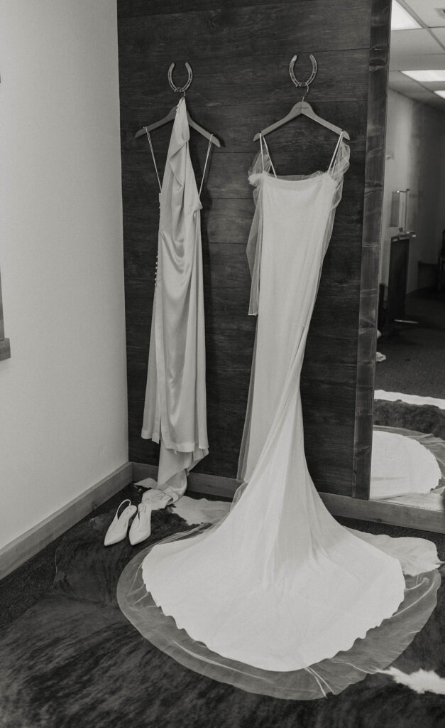 black and white photo of the bride's two dresses hung up at kinship ranch
