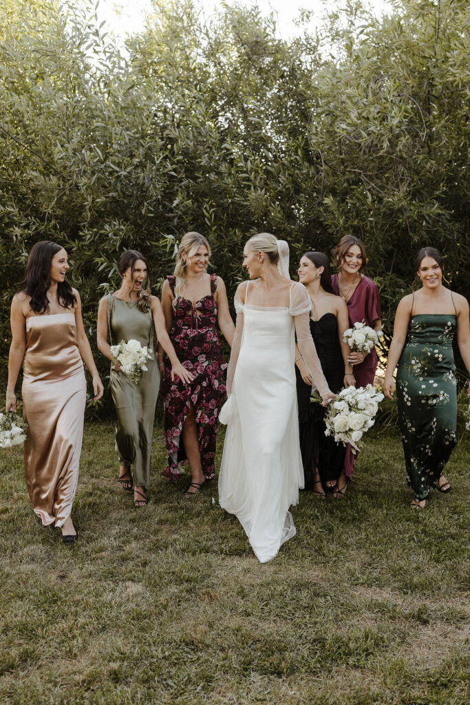 bridesmaids with neutral earth colors smiling and walking at kinship ranch