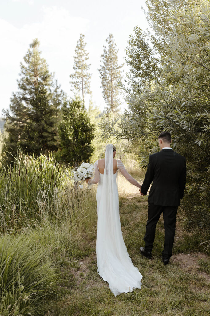 bride and groom walking into the forest at kinship ranch
