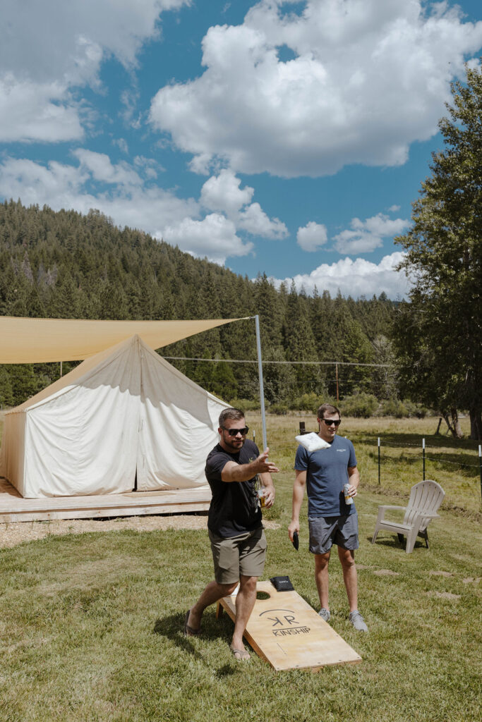 guests playing corn hole outside the tents at kinship ranch