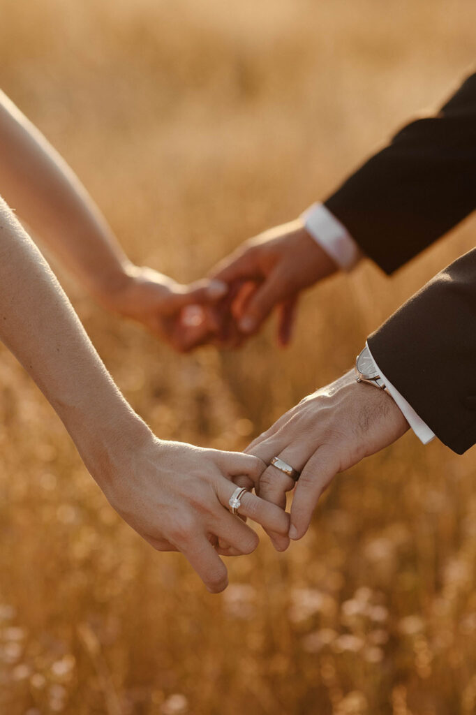 bride and grooms fingers interlocked showing rings at sunset at kinship ranch